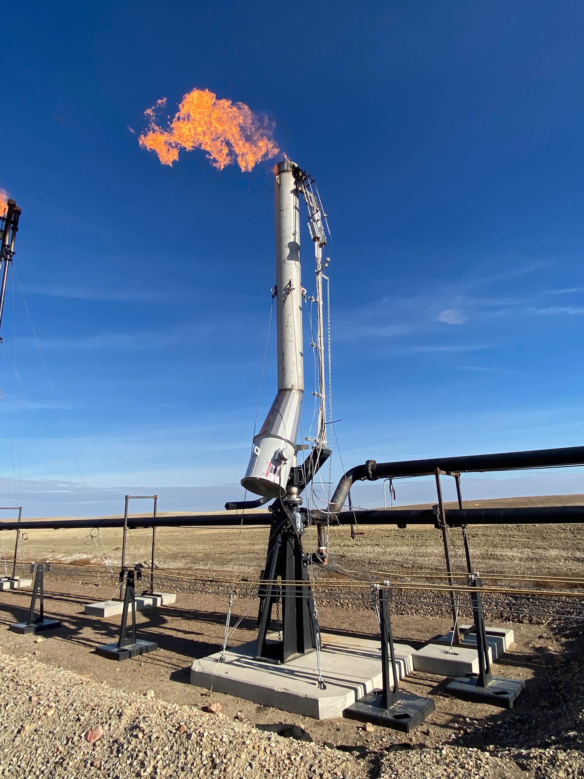 An Air Assist Flare burns a smokeless, bright orange flame on an oil site
